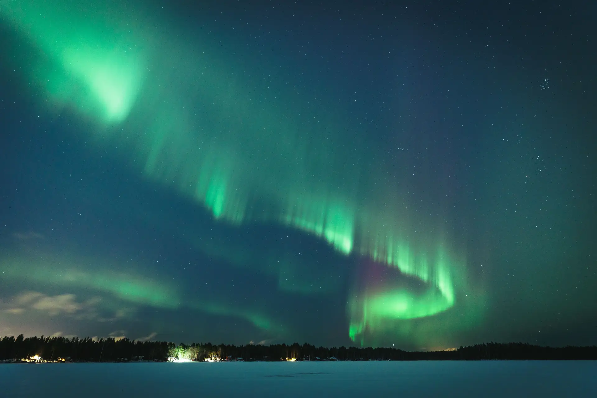 Revontulet lumisen maiseman yllä
